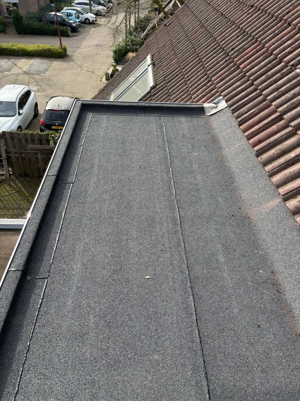 Nieuw bitumen dakvlak naast een pannendak na renovatie