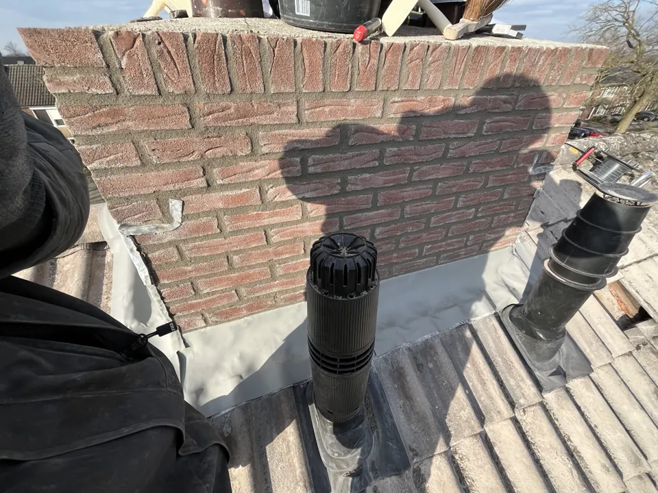Afgerond loodwerk met ontluchtingsdoorvoeren rond een schoorsteen
