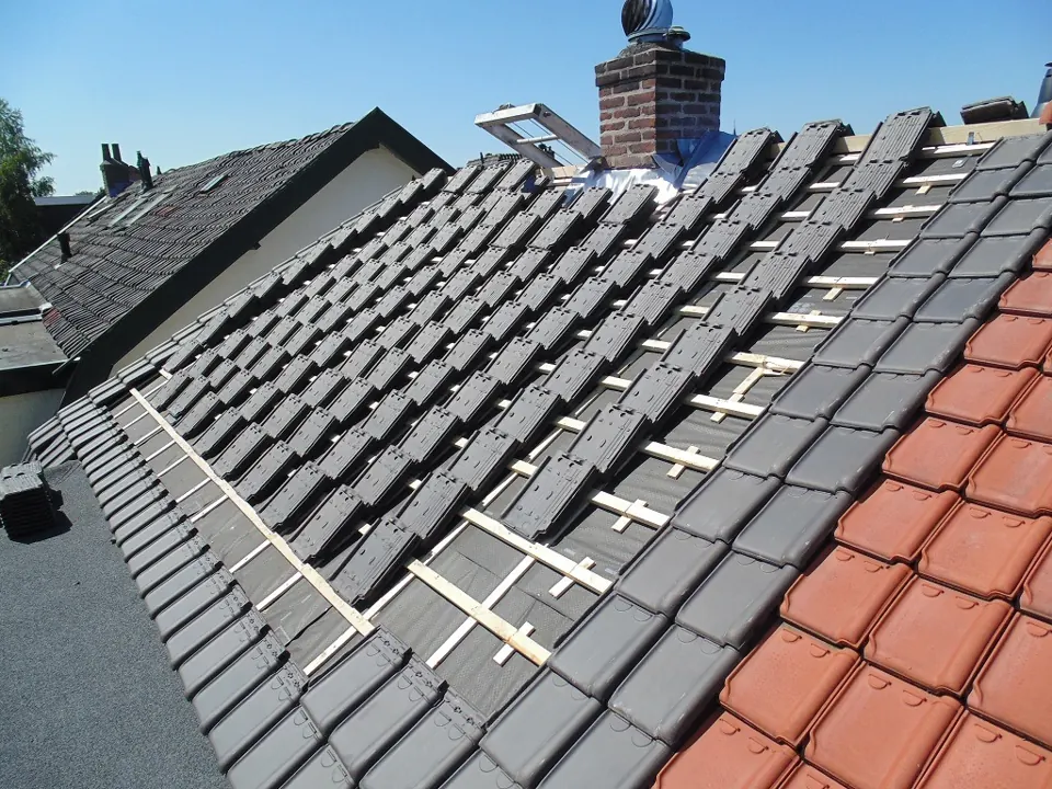 Pannendakrenovatie in uitvoering: nieuwe pannen op panlatten naast het bestaande dakvlak